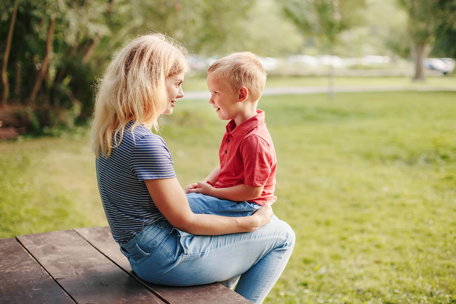 A child sitting on his mother's lap talking to her.