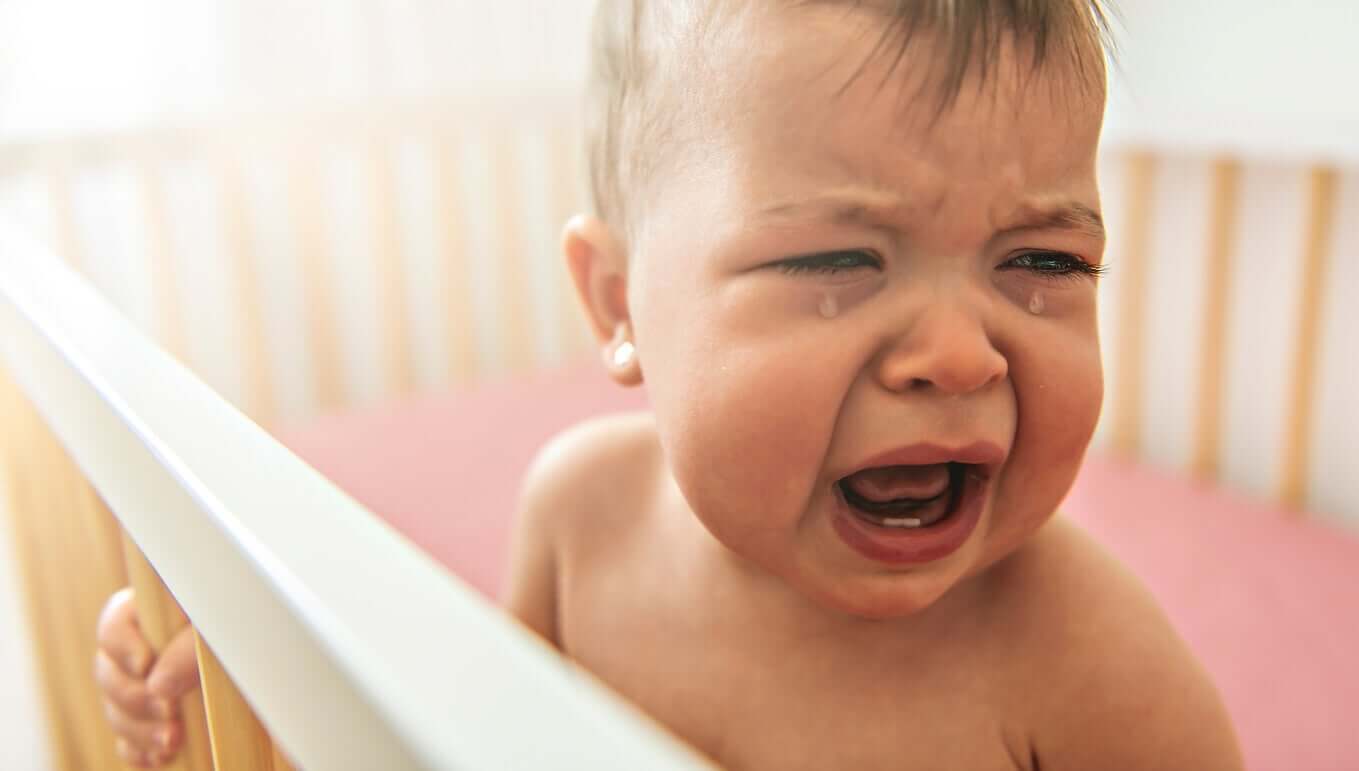 En baby som gråter i sengen sin.