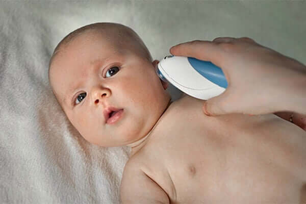 A woman taking a baby's temperature with an ear thermometer.
