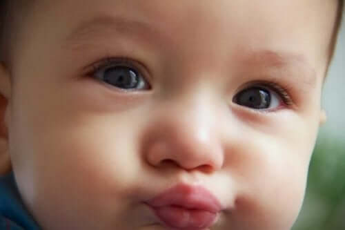 Een baby tuit zijn lippen om een kusje te geven