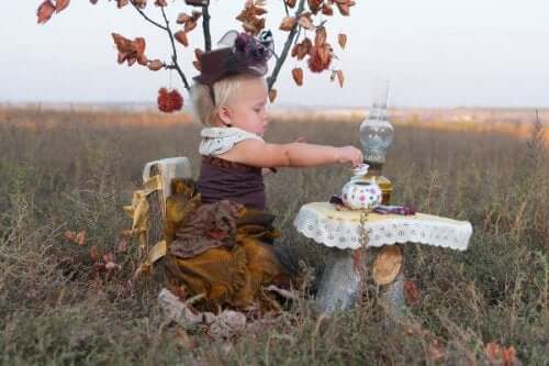 A toddler having a tea party in a field.