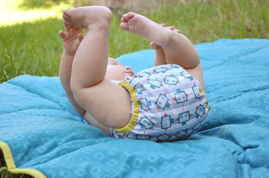 A baby playing on the ground wearing a diaper.