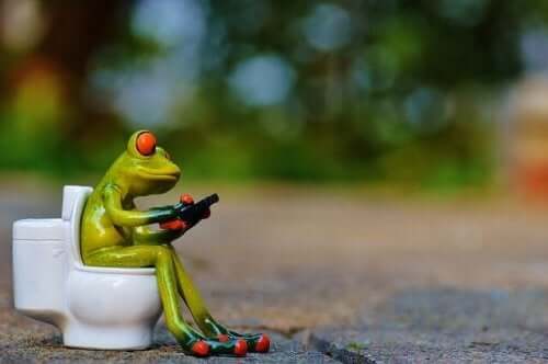 A toy frog sitting on a toy toilet.
