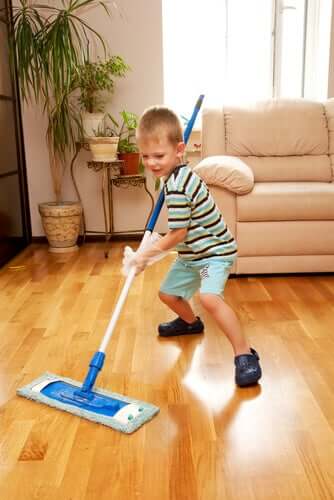 A young boy mopping a wooden floor.