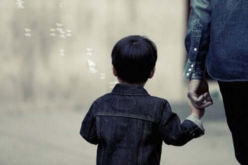 Ett barn som håller sin förälders hand och blåser bubblor.