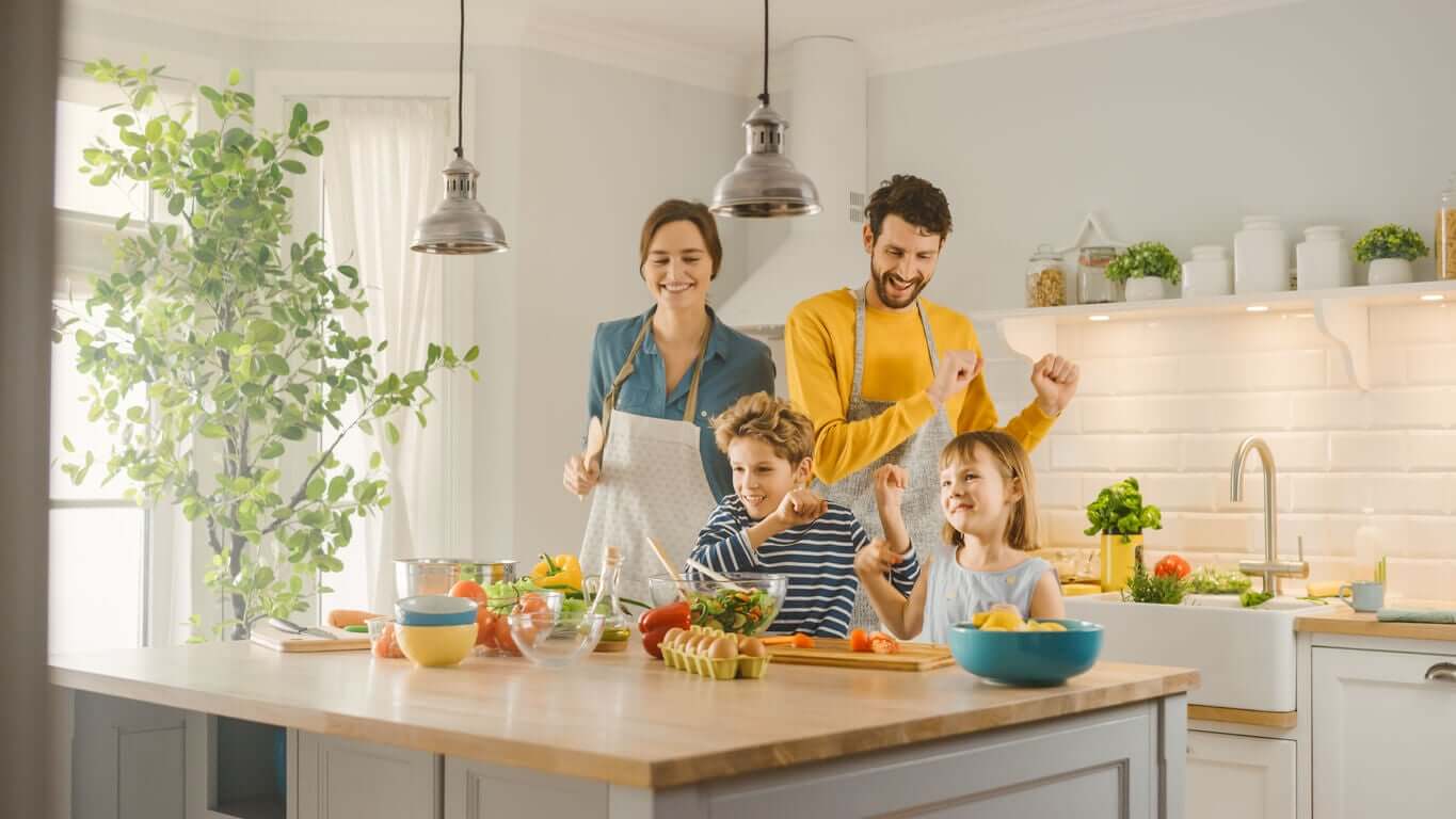 A family dancing while they cook together.