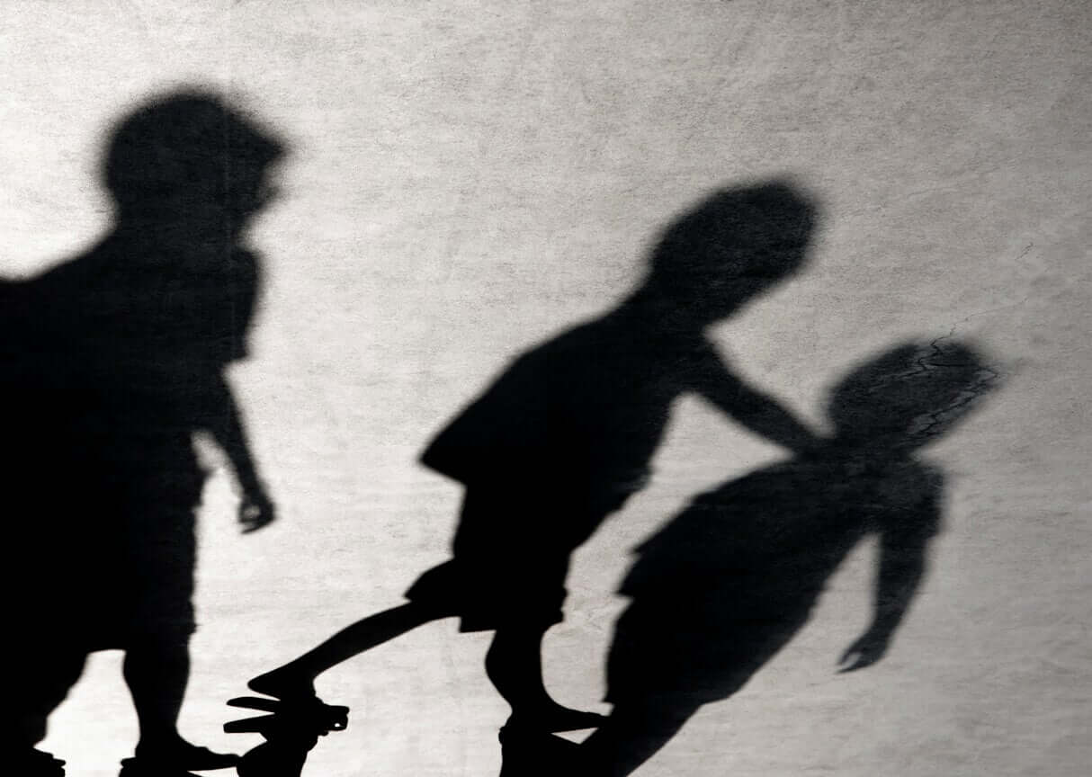 The shadows of chidren bullying another child.