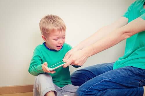 A mother taking a tablet away from a screaming toddler.