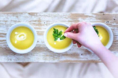 A woman adding parsley to bowls of creamy soup.
