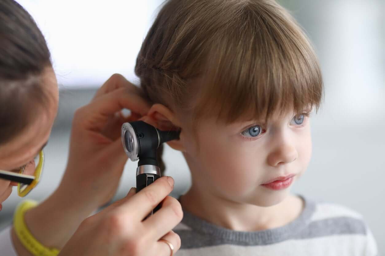 En lege ser inn i øret til en liten jente.