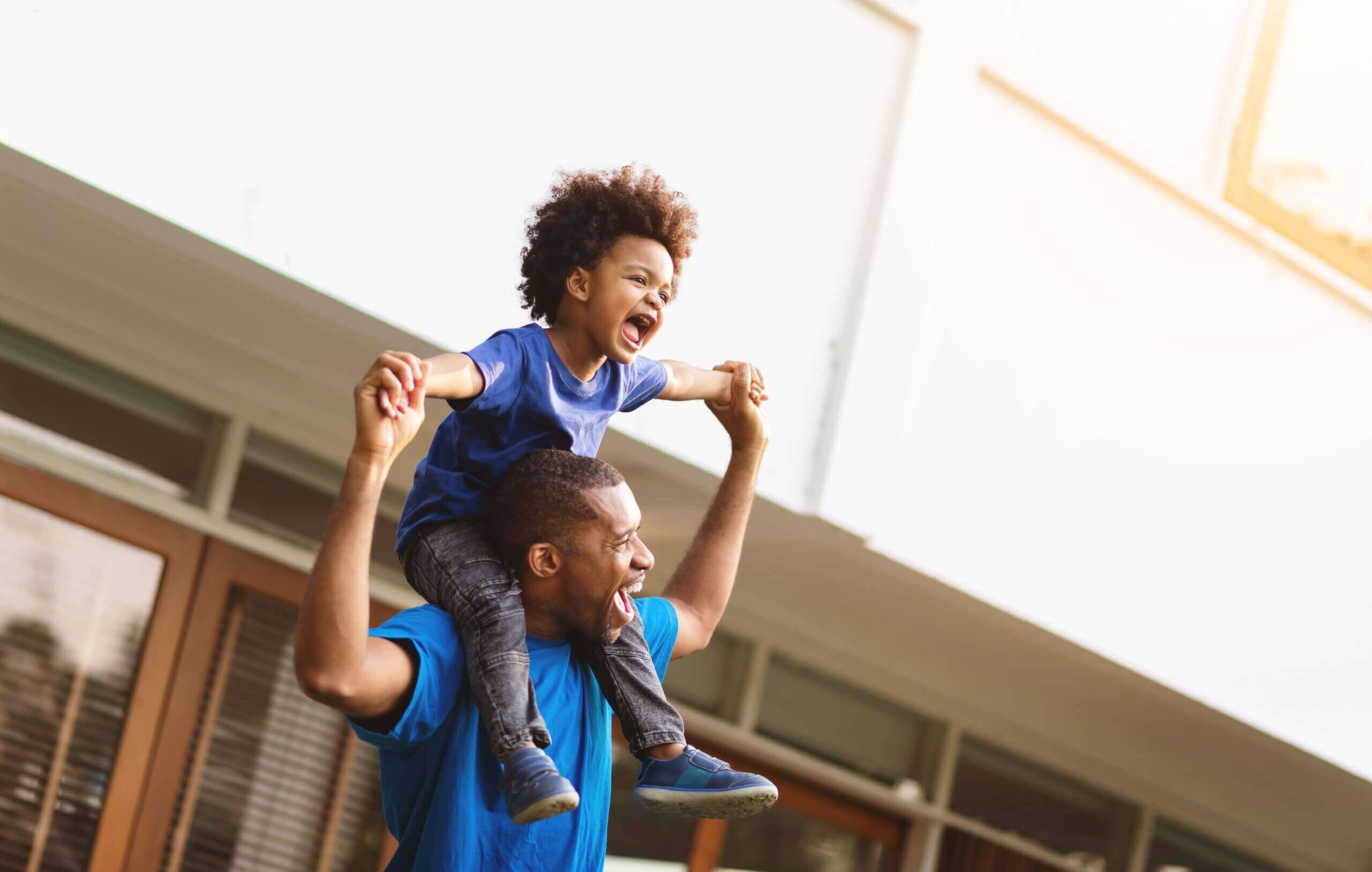 A father carrying his toddler son on his shoulders.