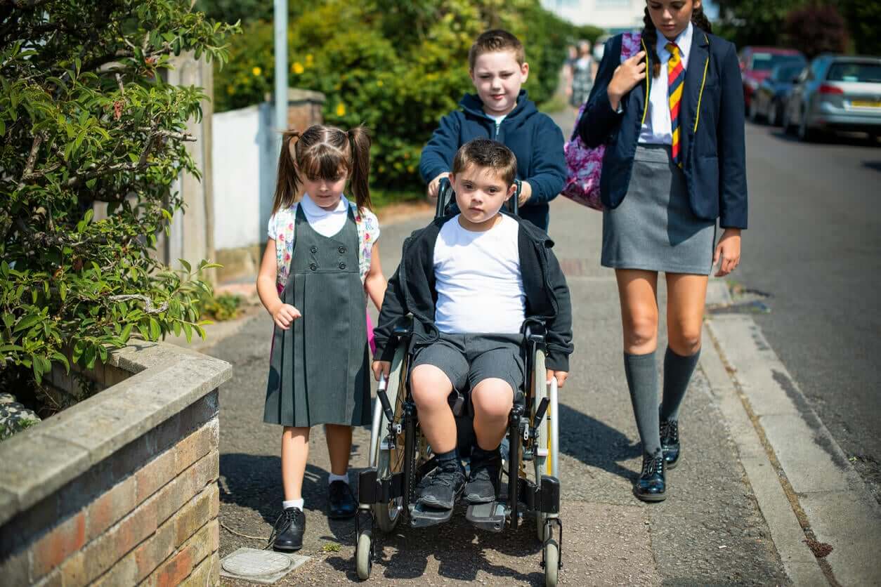 Four siblings walking to school, one in a wheelchair.