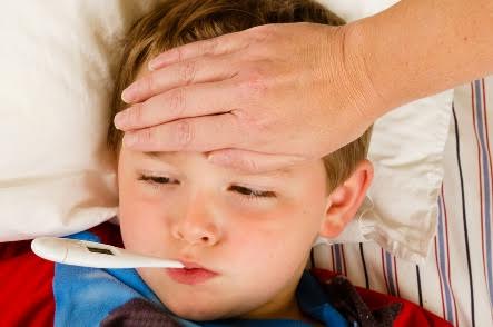 A woman feeling a boy's forehead and taking his temperature.