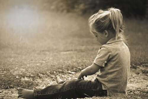 Een meisje zit alleen in het gras
