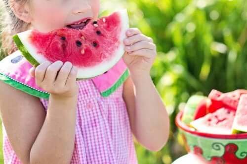 A young girl biting into a watermelon slice.