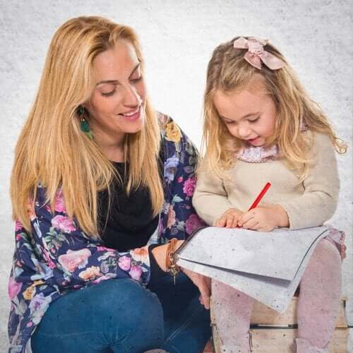 A mother watching her toddler daughter drawing on paper.
