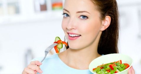A woman eating a fresh salad.