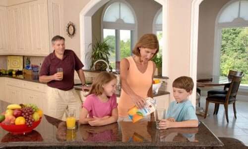 A family drinking orange juice in the kitchen.