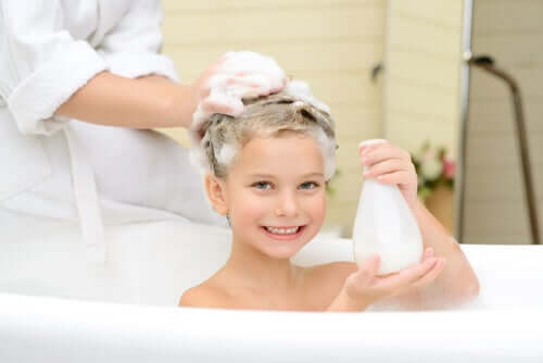 En liten jente som vasker håret i badekaret.