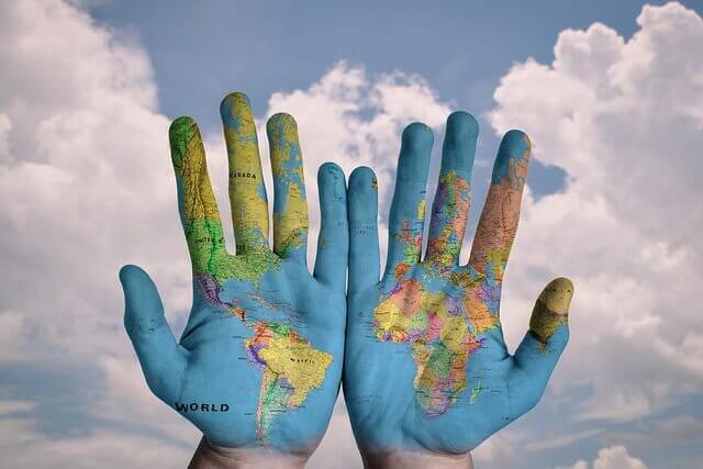 Hands with the map of the world on them.