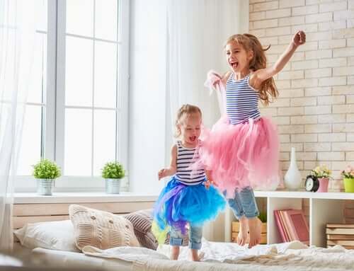 Girls wearing tutus and jumping on the bed.