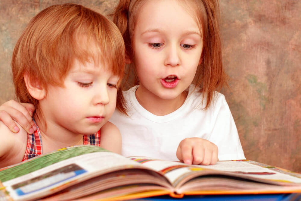 A little girl reading to her little brother.