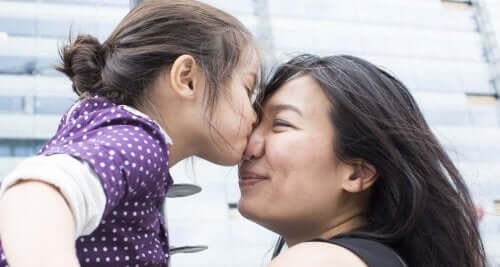 A little girl giving a woman a kiss on the nose.