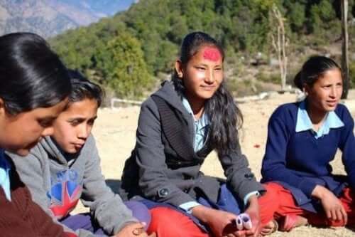 Children sitting in a circle outdoors.