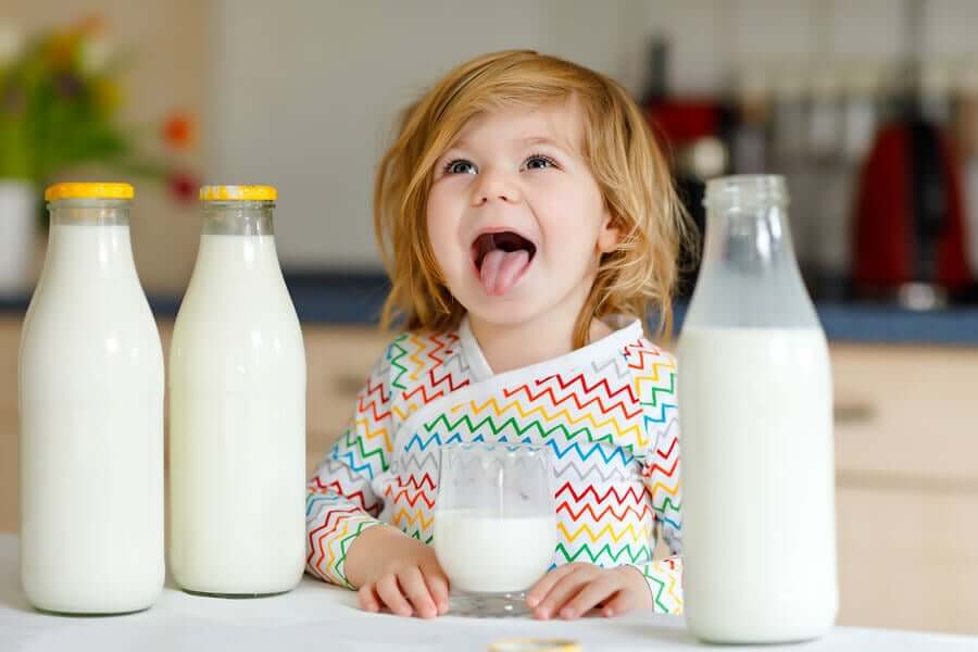 En liten jente som drikker melk og smiler.