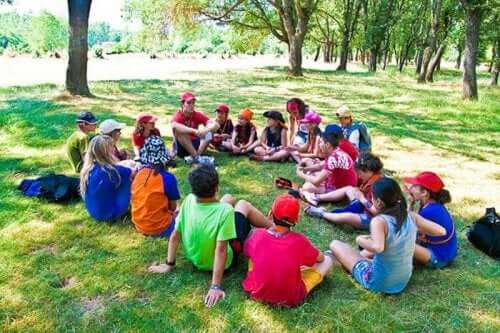 A large group of children siitting in a circle looking at an adult.