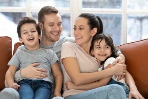 A family hugging and smiling on a couch.