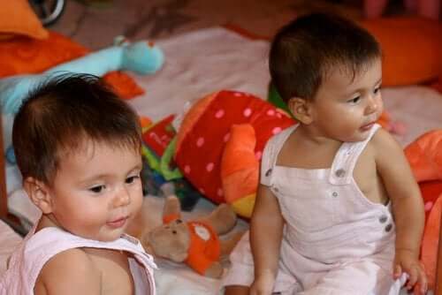 Tvillingguttebabyer sitter på gulvet.