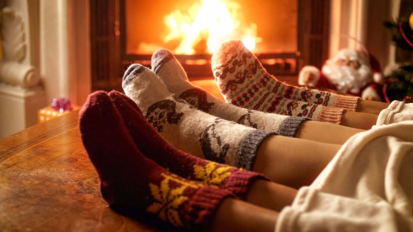 A woman and two children wearing wool socks near a fireplace.