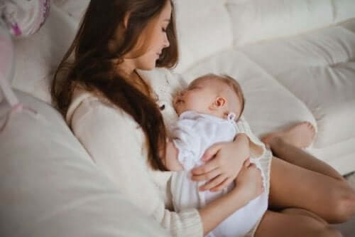 A woman looking down at her sleeping baby in her arms.