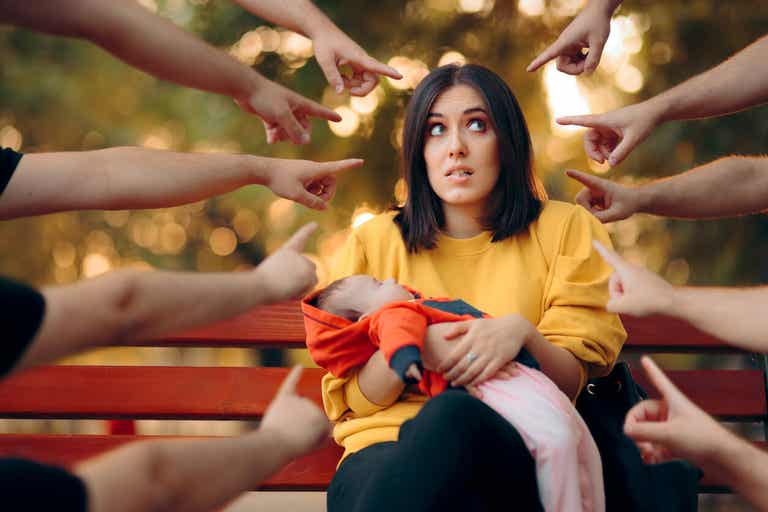 En kvinna som döms medan hon håller sitt barn och sitter på en parkbänk.