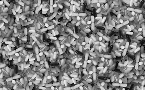 A black and white photo of a pile of pills and capsules.