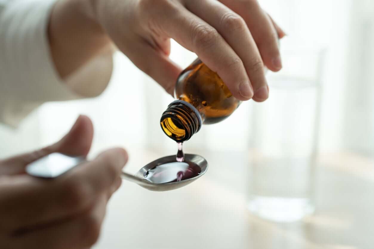 A woman pouring cough syrup into a spoon.