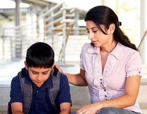 A child looking discouraged, and woman sitting next to him with her hand on his shoulder.