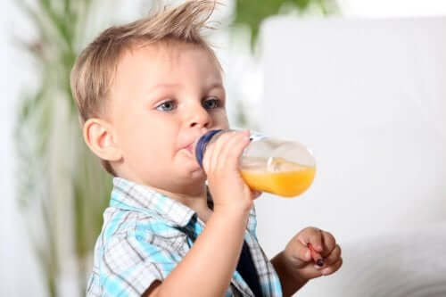 A toddler drinking juice from a bottle.