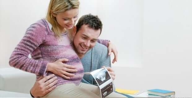 A pregnant couple looking at their ultrasound images.
