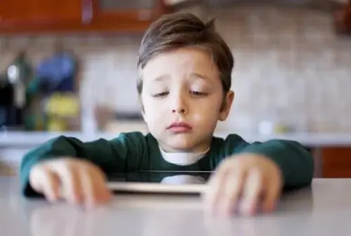 A child looking sadly at a tablet.