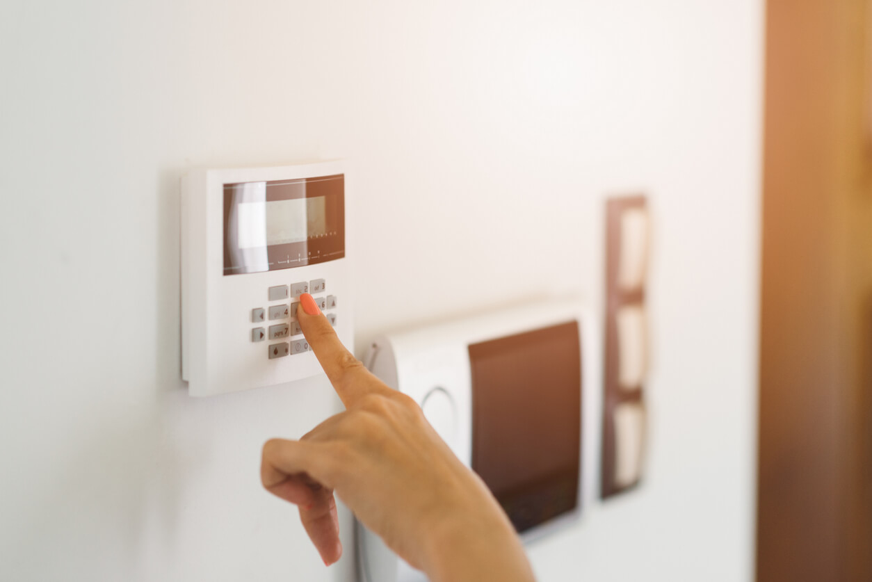 A woman setting the alarm system of her home.