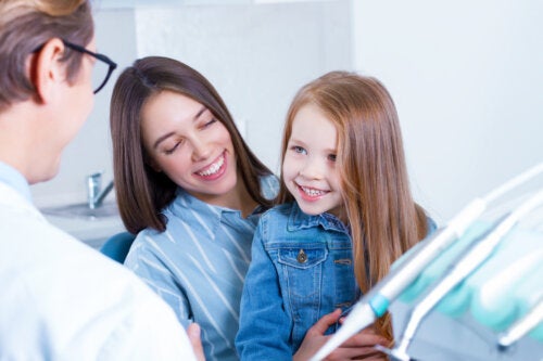 A dentist talking to a mother and daughter about the oral health of children.