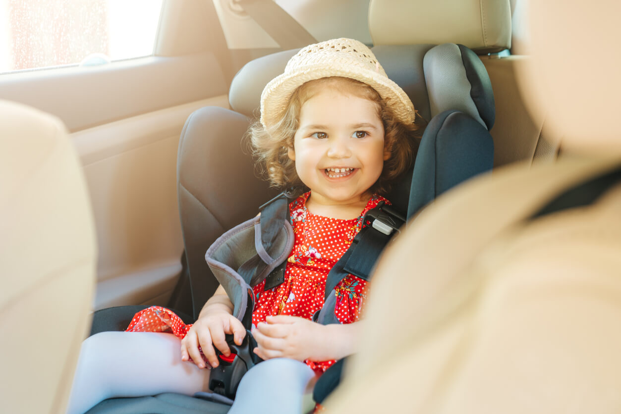 A toddler girl travelling by car happily in her carseat.