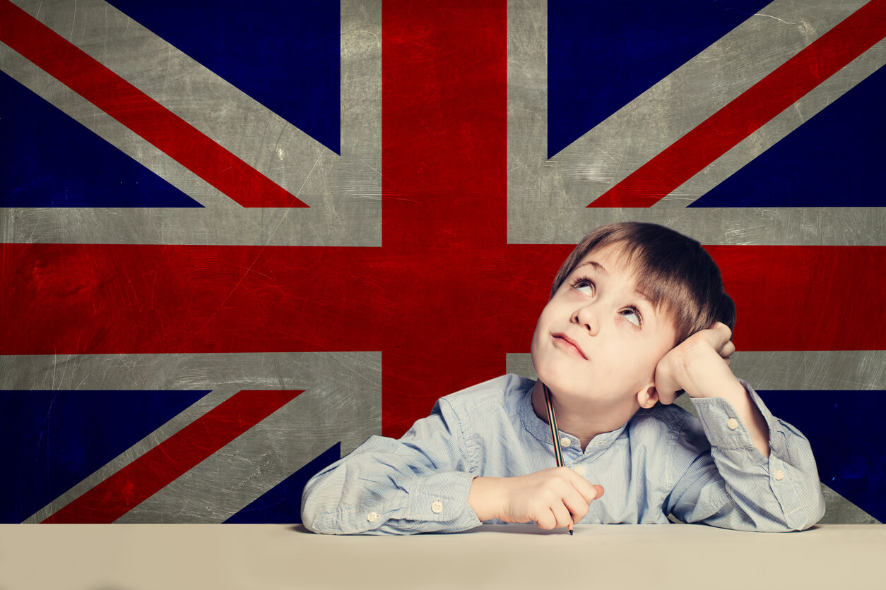 A thoughtful looking child sitting in front of the British flag.