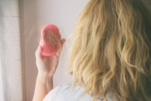 A woman looking at hair in her hairbrush.