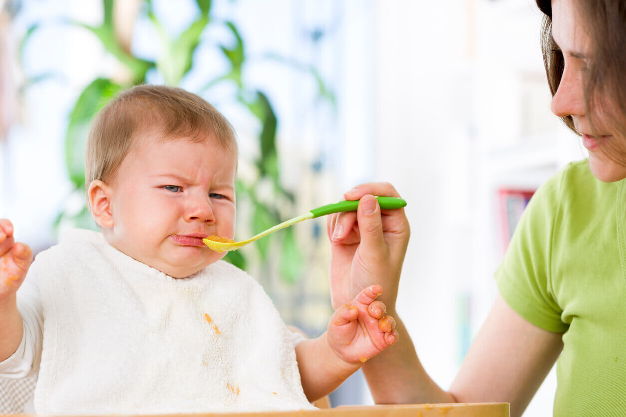 A baby refusing a spoonful of puree.