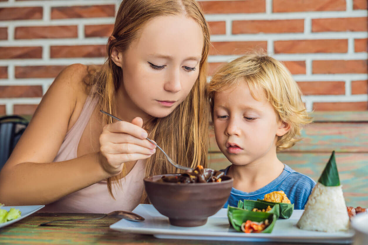 A mother helping to feed her young son.