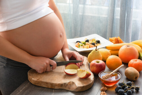 A pregnant woman chopping fruit.