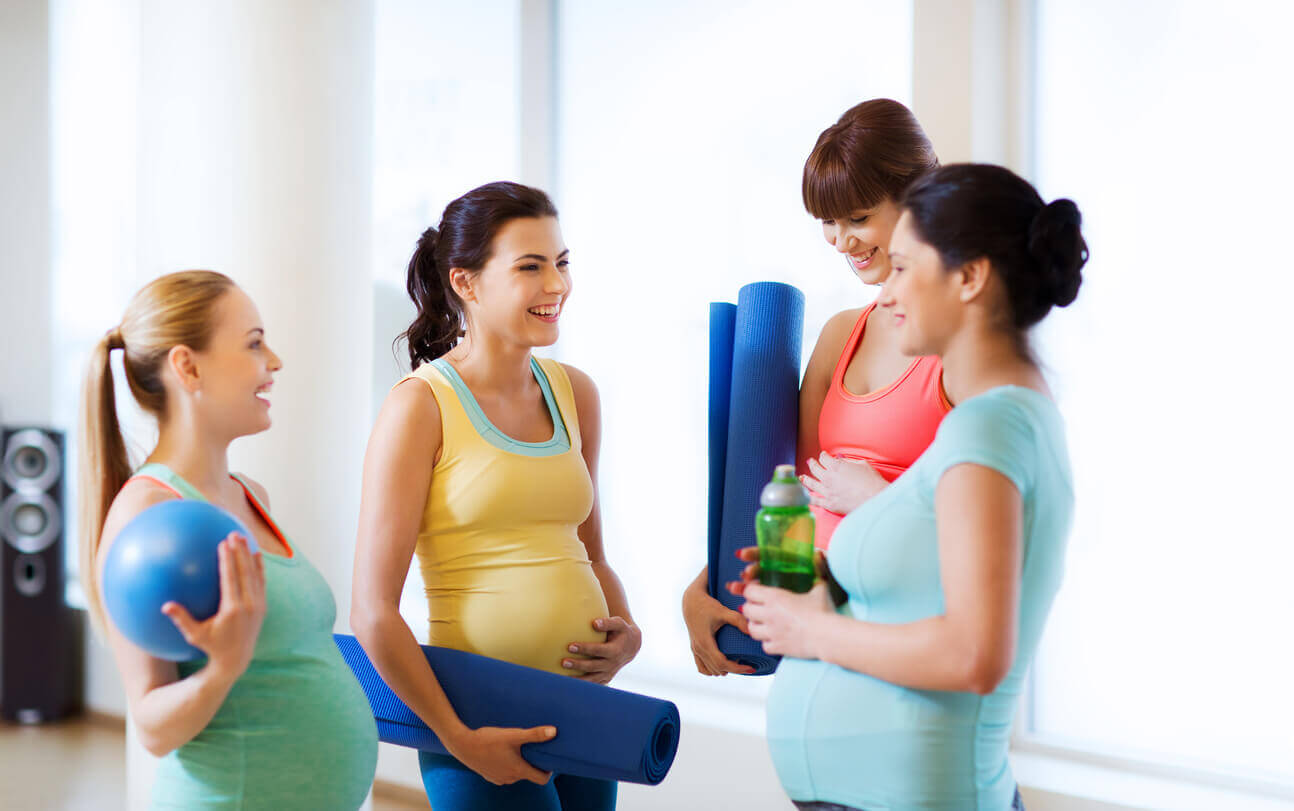Gravide kvinner som trener på treningssenteret sammen.